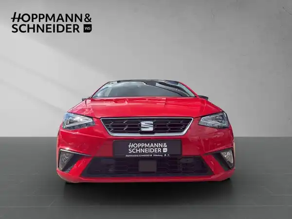 Das Bild zeigt einen roten SEAT Ibiza aus der Frontalansicht, mit dem Händlerlogo von Hoppmann & Schneider im Bild.