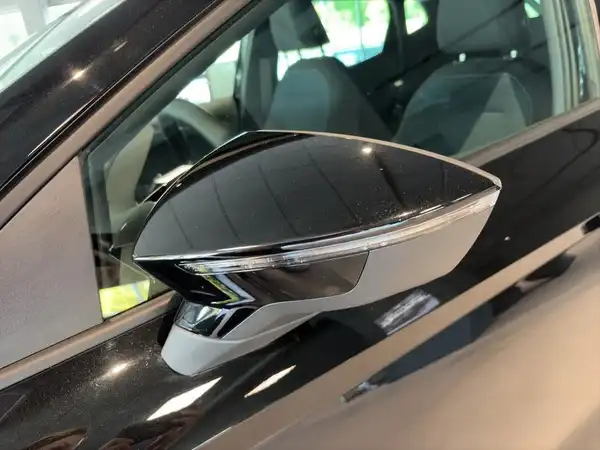 Das Bild zeigt den Seitenspiegel eines schwarzen SEAT IBIZA. Es handelt sich um eine Seitenaufnahme des Fahrzeugs.