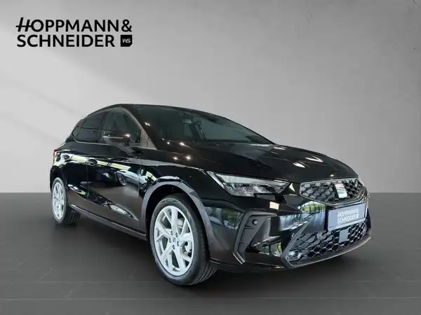 Ein Bild eines schwarzen SEAT IBIZA von der Seite, mit dem Händelrlogo "Hoppmann & Schneider" im Hintergrund.