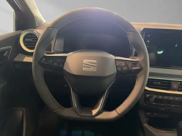 Das Bild zeigt das Innere eines SEAT IBIZA mit einem schwarzen Lenkrad und Armaturenbereich.