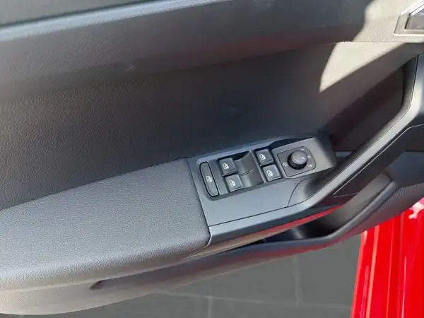 Innenaufnahme des Fahrzeugs mit einem roten Exterieur, zeigt die Türverkleidung und Schalter.