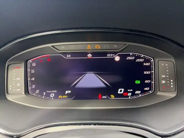 Das Bild zeigt das digitale Cockpit eines Fahrzeugs mit einer zentralen Anzeige. Es handelt sich um eine Innenaufnahme, die hauptsächlich in Schwarz gehalten ist.