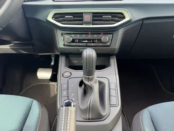 Das Bild zeigt das Innere eines Fahrzeugs, aufgenommen aus der Perspektive des Fahrerplatzes mit einem Fokus auf die Mittelkonsole und Sitzfarbe in dunkelblau und schwarz.