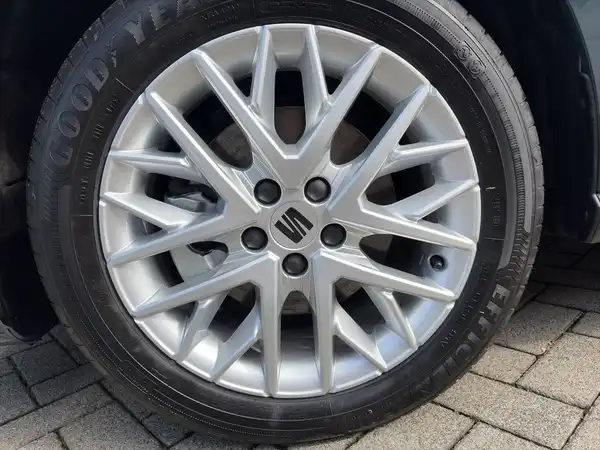 Das Bild zeigt eine Aufnahme von der Seite eines Fahrzeugs, wobei der Fokus auf dem Rad mit einer silbernen Felge liegt.