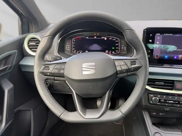 Das Bild zeigt das Innere eines SEAT IBIZA mit einem schwarzen Interieur. Es ist eine Innenaufnahme des Fahrzeugs, das Armaturenbrett und das Lenkrad sind sichtbar.