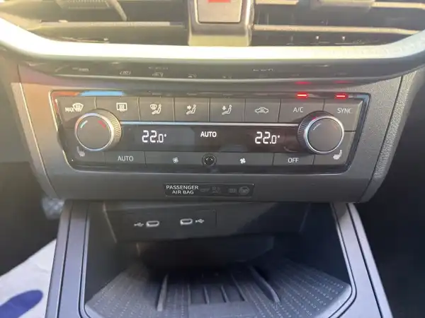 Das Bild zeigt das Innenraum eines Fahrzeugs mit Bedienknöpfen für die Klimaanlage und einem schwarzen Interieur.