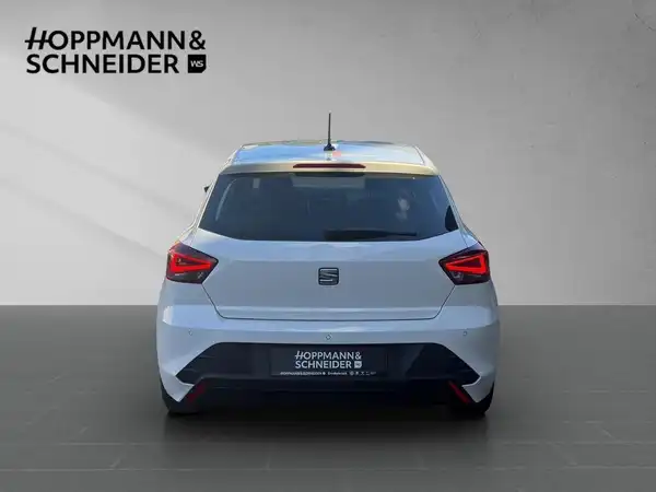 Das Bild zeigt die Rückansicht eines weißen SEAT IBIZA. Im oberen Bereich ist das Händlerlogo von HOPPMANN & SCHNEIDER sichtbar.