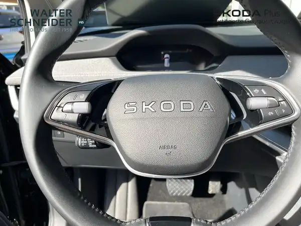 Innenaufnahme des Fahrzeugs ŠKODA ENYAQ iV, schwarzes Interieur, mit Händlerlogo.