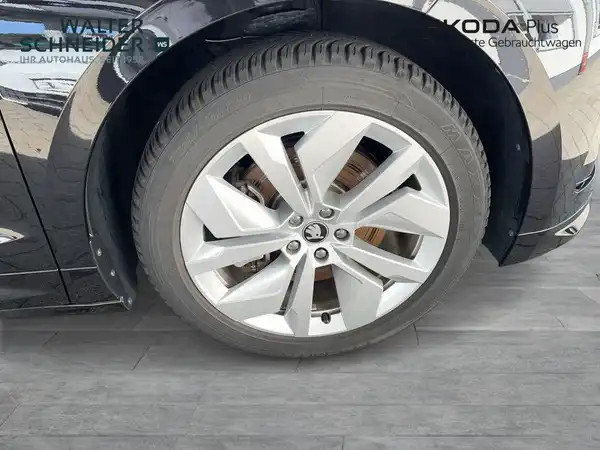 Das Bild zeigt einen seitlichen Blick auf das Rad eines schwarzen ŠKODA ENYAQ iV mit Händlerlogo und markanten Texteinblendungen.