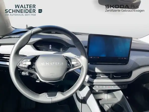 Das Bild zeigt das Interieur eines ŠKODA ENYAQ iV. Das Fahrzeug hat ein schwarzes Interieur. Im Bild ist das Händlerlogo sichtbar.