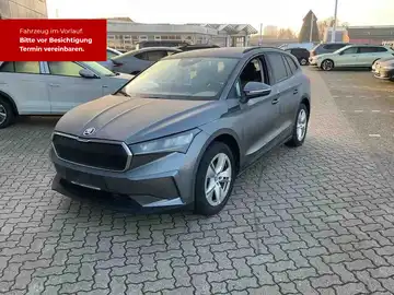 Das Bild zeigt einen grauen ŠKODA ENYAQ iV von vorne, mit markanten Texteinblendungen auf rotem Hintergrund, die auf einen bevorstehenden Termin hinweisen.
