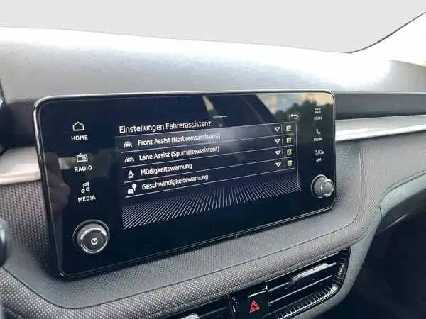 Innenaufnahme des Fahrzeugs mit einem Bildschirm, der verschiedene Einstellungen anzeigt.