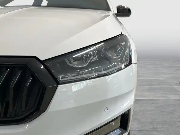 Das Bild zeigt einen weißen ŠKODA FABIA von vorne, mit Fokus auf den Scheinwerfern.
