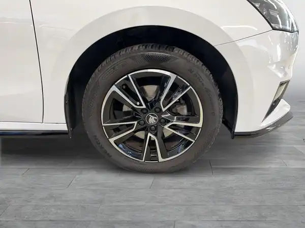 Das Bild zeigt die Seite eines weißen Fahrzeugs mit einem Fokus auf dem Rad und der Felge.