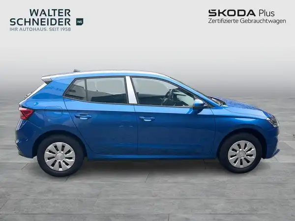 Das Bild zeigt einen blauen ŠKODA FABIA von der Seite. Es enthält das Händlerlogo und markante Texteinblendungen.