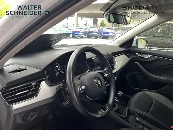 Das Bild zeigt das Inneninterieur eines ŠKODA KAMIQ. Es ist eine Aufnahme aus dem Innenraum, mit einem schwarzen Interieur. Das Händlerinstitution ist im Bild eingeblendet.