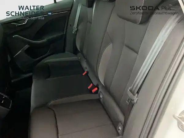Das Bild zeigt den Innenraum eines ŠKODA KAMIQ von der Rücksitzbank. Die Sitze sind in Schwarz gehalten und das Händlerlogo ist vorhanden.