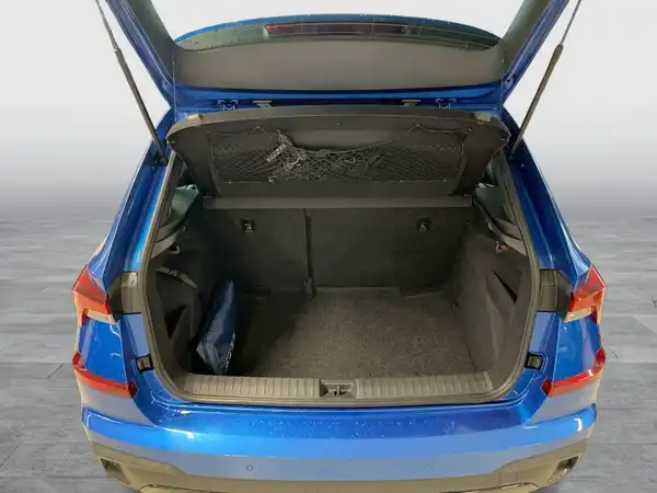 Das Bild zeigt den Kofferraum eines blauen ŠKODA KAMIQ aus der Rückansicht.