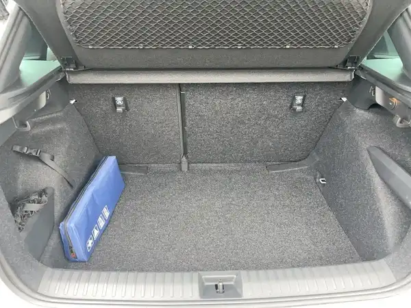 Das Bild zeigt den Kofferraum eines ŠKODA KAMIQ von hinten. Der Kofferraum ist mit schwarzem Material ausgekleidet und enthält eine blaue Tasche.