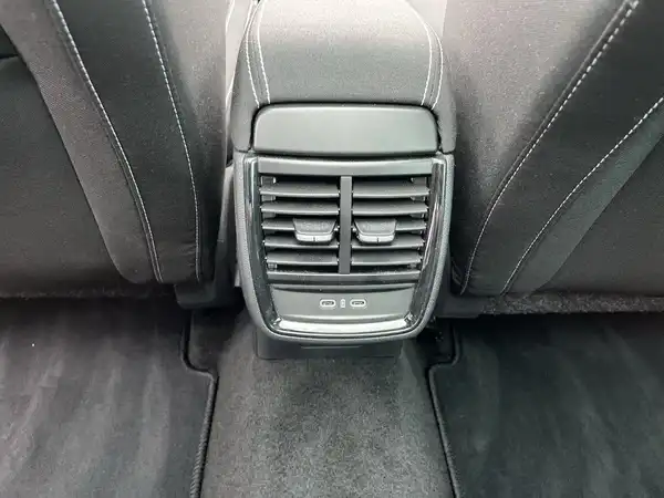 Innenaufnahme eines Fahrzeugs, Fokus auf die hintere Belüftung sowie den Bodenbelag, in Schwarz.