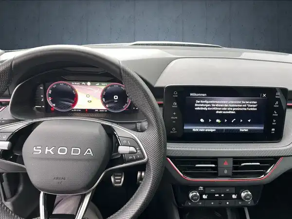 Innenaufnahme des ŠKODA KAMIQ mit schwarzem Interieur. Das Bild zeigt das Lenkrad und das Infotainmentsystem.