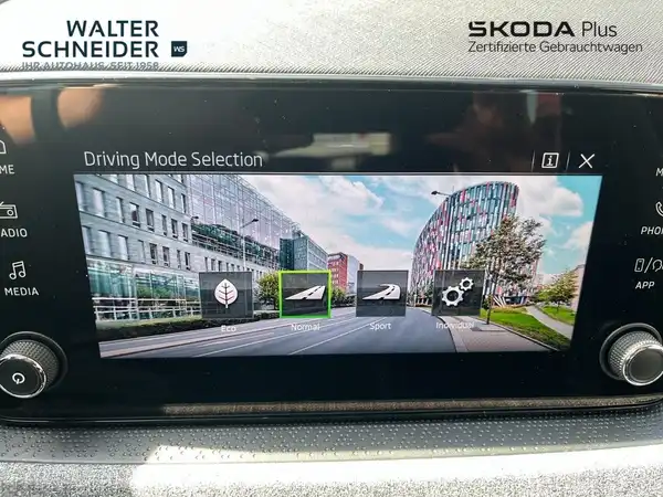 Das Bild zeigt den Innenraum eines ŠKODA KAMIQ mit einem Navigationsdisplay, das verschiedene Fahrmodi anzeigt. Das Interieur ist schwarz und die Anzeige enthält das Händlerlogo 'WALTER SCHNEIDER'.