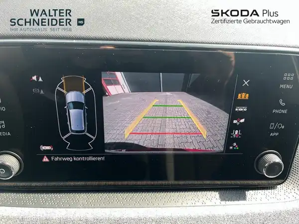Dies ist eine Innenaufnahme des Fahrzeugs, die das Navigations- und Rückfahrkamera-Display zeigt. Das Fahrzeug ist nicht direkt sichtbar, aber man sieht die Innenraumausstattung und das Gerät mit einer Rückfahransicht.