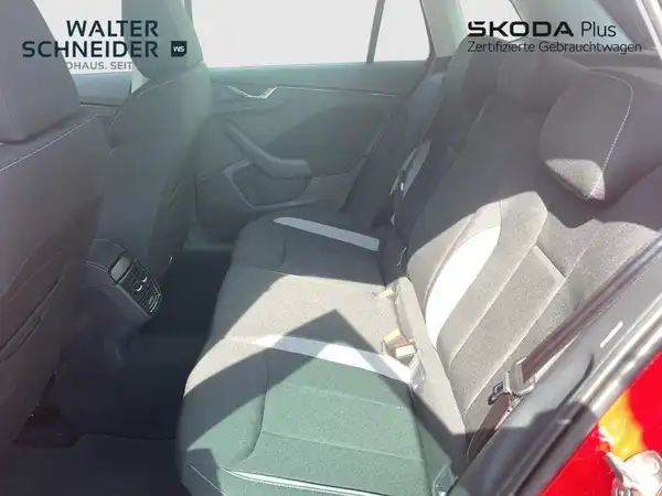 Aufnahme des Innenraums des ŠKODA KAMIQ von hinten, zeigt die Rücksitze in schwarzem Innenraum mit hellen Akzenten, inklusive Händlerinformationen.