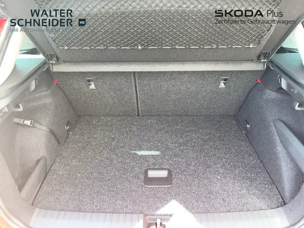 Das Bild zeigt den Kofferraum eines ŠKODA KAMIQ aus der Innenansicht. Der Kofferraum hat eine graue Teppichverkleidung und es sind Händlerinformationen sichtbar.