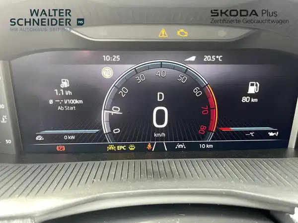 Das Bild zeigt das Armaturenbrett eines ŠKODA KAMIQ mit schwarzem Interieur. Der Bildschirm zeigt Fahrdaten und -informationen. Oben ist das Händlerlogo zu sehen.