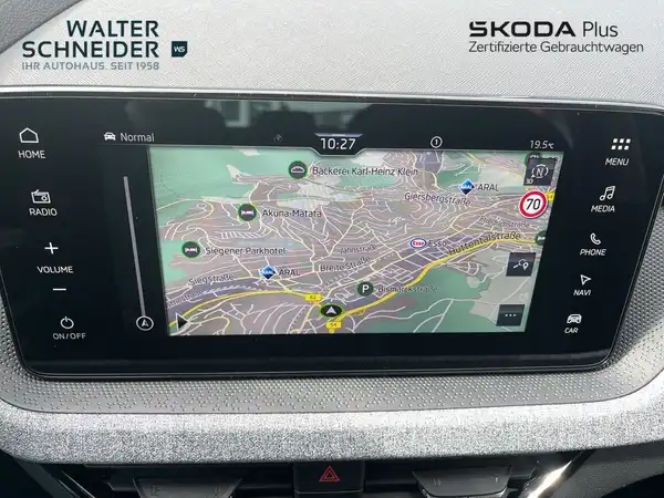 Das Bild zeigt das Innere eines ŠKODA KAMIQ mit einem Navigationsdisplay, die Interieurfarbe ist schwarz/silber. Es sind Händlerlogos und markante Texteinblendungen sichtbar.