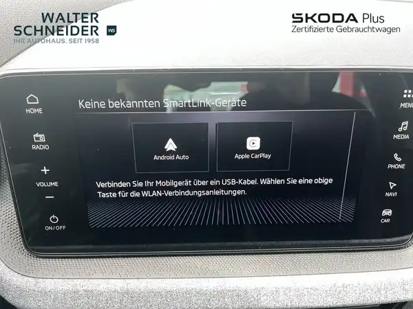Eine Innenaufnahme des ŠKODA KAMIQ mit schwarzem Interieur, die ein Informationsdisplay zeigt, das auf SmartLink-Geräte hinweist.