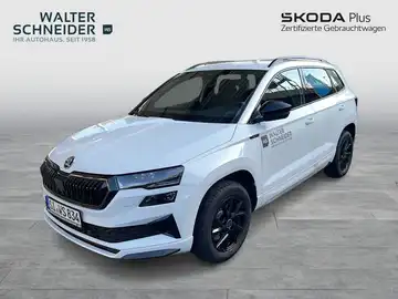 Das Bild zeigt einen weißen ŠKODA KAROQ aus der Frontansicht. Es enthält das Händelerslogo von Walter Schneider und zusätzliche Texteinblendungen.
