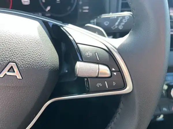 Das Bild zeigt eine Innenaufnahme des Fahrzeugs, die das Lenkrad und Schaltknöpfe zeigt. Die Interieurfarbe ist schwarz.
