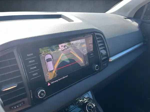 Dieses Bild zeigt eine Innenaufnahme des ŠKODA KAROQ mit einem Bildschirm, der eine Rückfahrkamera-Anzeige zeigt. Der Innenraum ist schwarz.