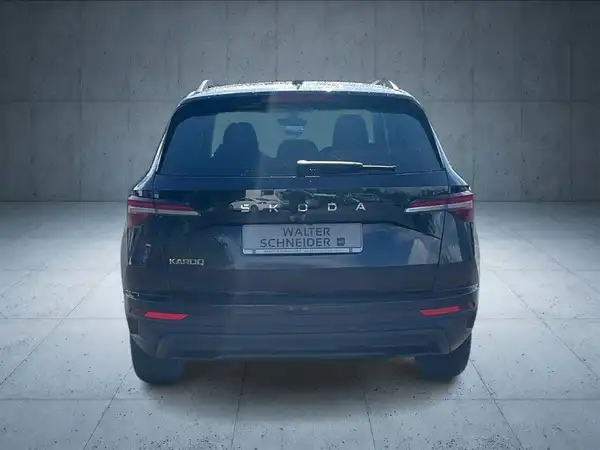 Das Bild zeigt einen schwarzen ŠKODA KAROQ aus der Rückansicht mit einem Händlerlogo und markanten Texteinblendungen.