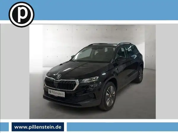 Das Bild zeigt einen schwarzen ŠKODA KAROQ, aufgenommen von vorne. Im Bild ist das Händlerlogo abgebildet.