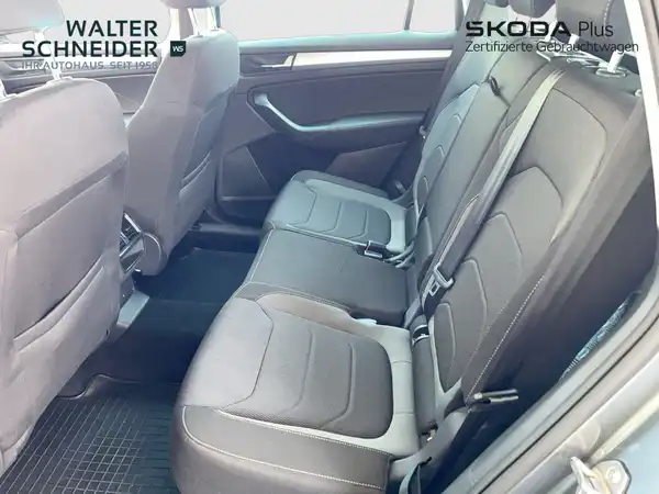 Eine Innenaufnahme des Rücksitzbereichs eines ŠKODA KODIAQ mit schwarzem Interieur. Das Händlerlogo ist sichtbar.