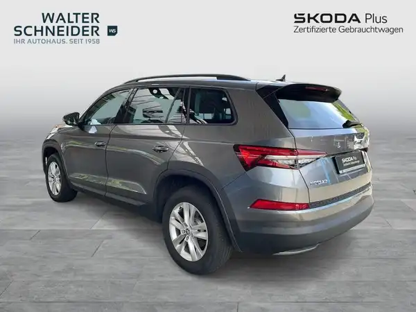 Das Bild zeigt einen grauen ŠKODA KODIAQ von der Seite, mit Händlerlogo und markanten Texteinblendungen.