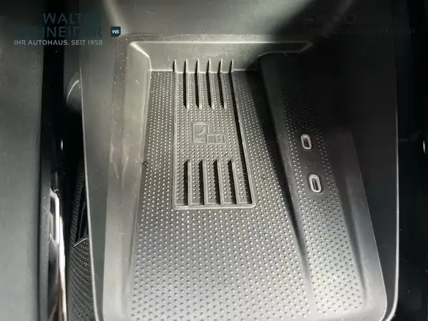 Das Bild zeigt eine Innenaufnahme des Fahrzeugs, speziell einen Blick auf das Ablagefach mit zwei USB-Anschlüssen. Die Interieurfarbe ist schwarz und es gibt ein Händlerlogo sowie markante Texteinblendungen auf dem Foto.