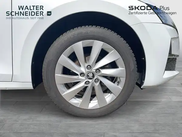 Das Bild zeigt eine Seitenansicht eines weißen ŠKODA OCTAVIA mit einem Sicht auf das Rad und Teil der Karosserie. Es sind Händlerlogos und markante Texteinblendungen vorhanden.