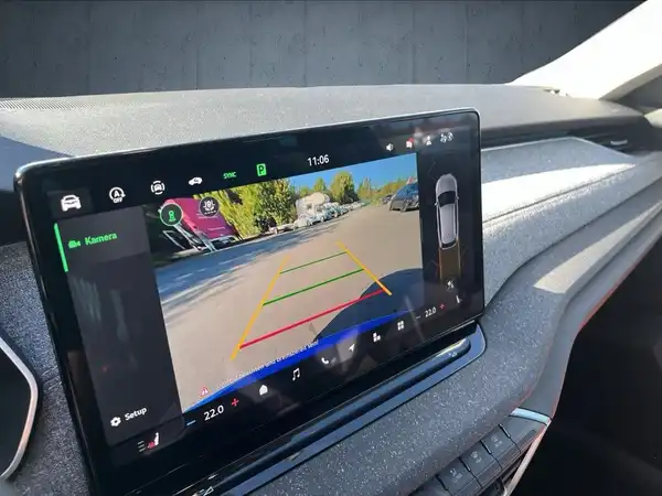 Das Bild zeigt den Innenraum des Fahrzeugs mit einem Display, das die Rückfahrkamera anzeigt, und hat ein schwarzes Interieur.