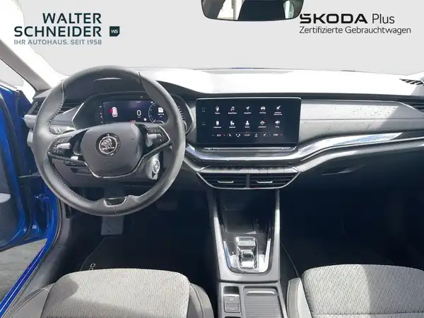 Das Bild zeigt das Inneninterieur eines ŠKODA OCTAVIA in Grau mit schwarzen Akzenten. Es sind auch Dealer-Logos zu sehen und es gibt markante Texteinblendungen.