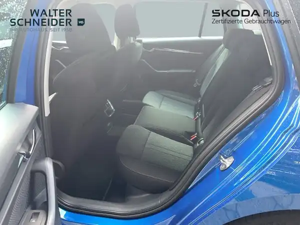 Innenaufnahme des Fahrzeugs, Blick auf die Rücksitze, Farbe des Fahrzeugs ist blau, Interieur ist schwarz. Händlerlogo ist eingeblendet und es gibt weitere Texteinblendungen.