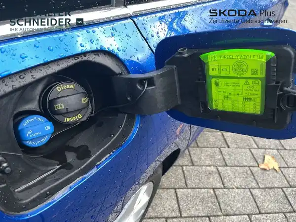 Das Bild zeigt die Tankklappe eines blauen ŠKODA OCTAVIA von der Seite, mit sichtbarem Händlerlogo und einigen Texteinblendungen.