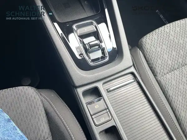 Detailaufnahme des Innenraums eines ŠKODA OCTAVIA, Sicht auf die Mittelkonsolentasten und -oberfläche, schwarz mit gestepptem Stoff, Händlerschriftzug sichtbar.