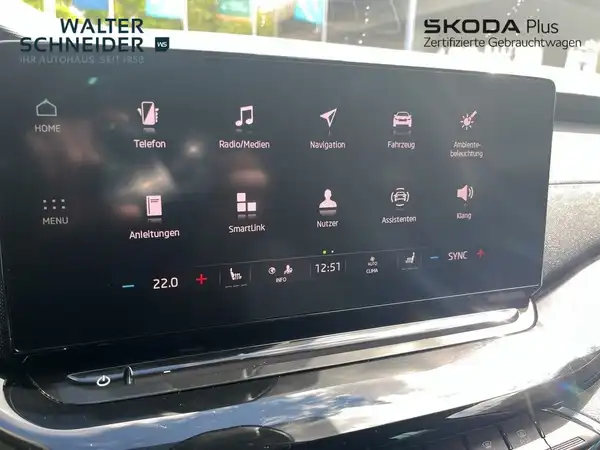 Das Bild zeigt das Innenraumdisplay eines ŠKODA OCTAVIA, aufgenommen aus der Innenansicht. Die Interieurfarbe ist schwarz. Es sind Händlerlogos und markante Texteinblendungen sichtbar.