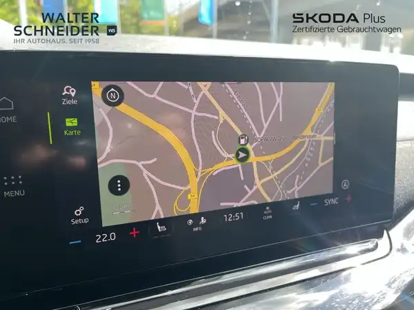 Das Bild zeigt das Navigationsgerät im Innenraum eines ŠKODA OCTAVIA. Auf dem Display ist eine Kartenansicht zu sehen. Das Händlerlogo ist eingeblendet.