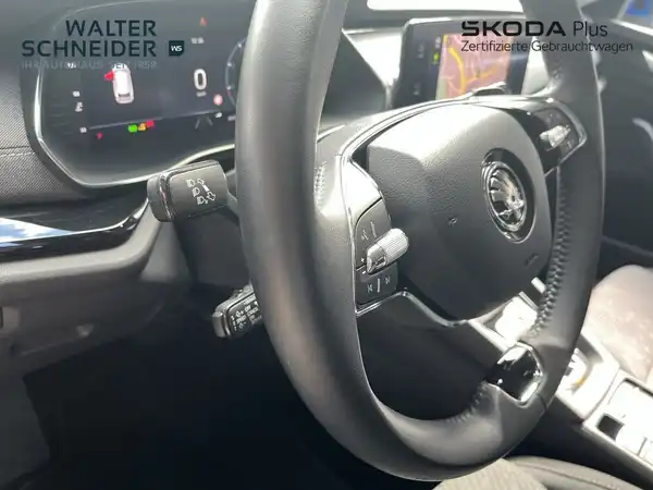 Das Bild zeigt den Innenraum eines ŠKODA OCTAVIA mit Blick auf das Lenkrad und das Armaturenbrett. Der Innenraum ist schwarz, und das Händlerinformationen ist sichtbar.