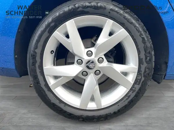 Das Bild zeigt eine Seitenansicht eines blauen ŠKODA OCTAVIA, aufgenommen von der Seite, mit einem sichtbaren Händlerlogo und markanten Texteinblendungen.